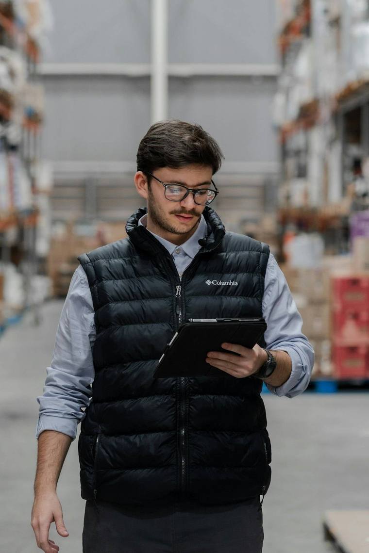 Encargado de depósito consultando una tablet entre estanterías
